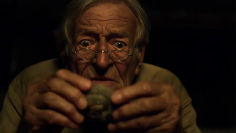 elderly man with glasses examining a mysterious object