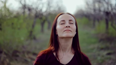 young woman enjoys nature, relaxes with her eyes closed. circular motion of the camera.