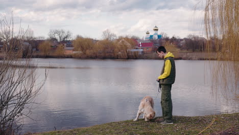 boy walking his dog by a river in a village