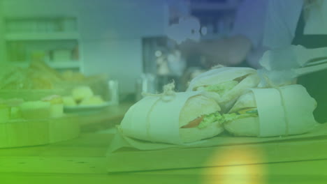 on table, sandwiches wrapped in paper with colorful animation overlay in kitchen