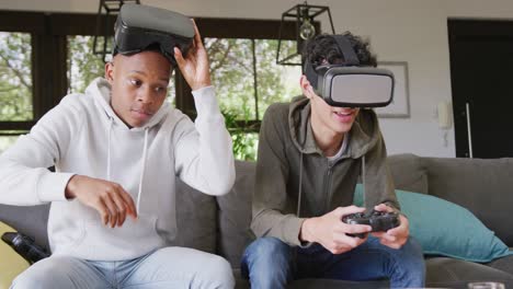 happy diverse male teenage friends playing video games and using vr headsets at home, slow motion