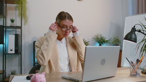 Businesswoman-working-on-laptop-at-office-wearing-earphones-listening-favorite-energetic-disco-music