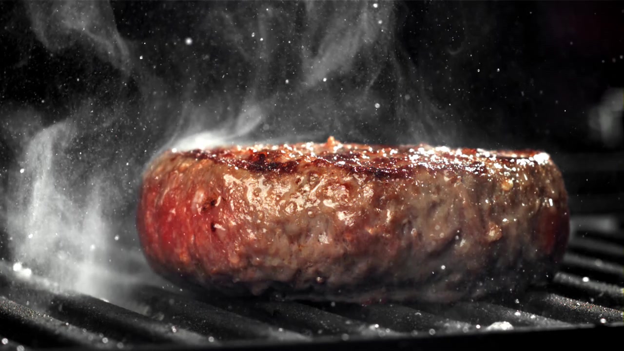 Slowmotion af en lækker burgerbøf, der syder på grillen