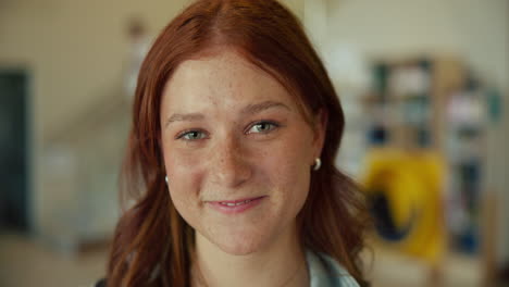 portrait of a smiling woman with red hair and freckles