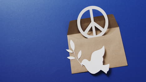 primer plano de paloma blanca con hoja, signo de paz blanco, sobre y espacio de copia sobre fondo azul