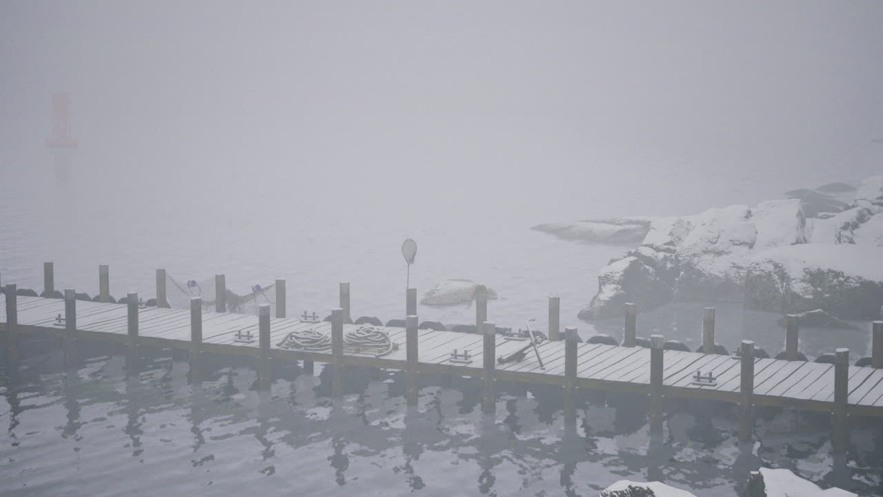 Misty winter dock with snow and icy water in a tranquil setting