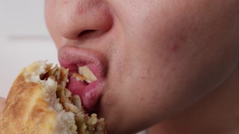 boca de un tipo asiático comiendo hamburguesa de pollo en cámara lenta de cerca