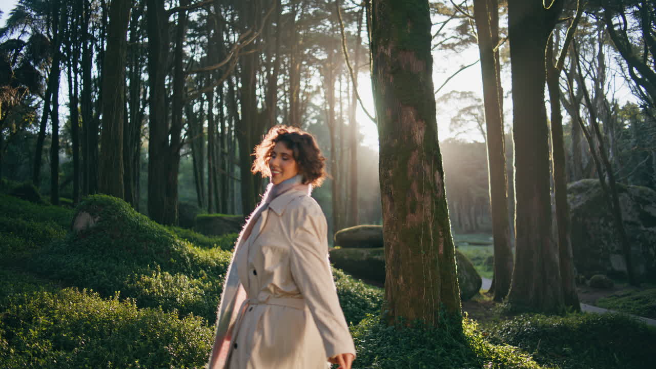 아침 숲을 회전하는 여자가 부드러운 빛으로 빛나고 행복을 느다.