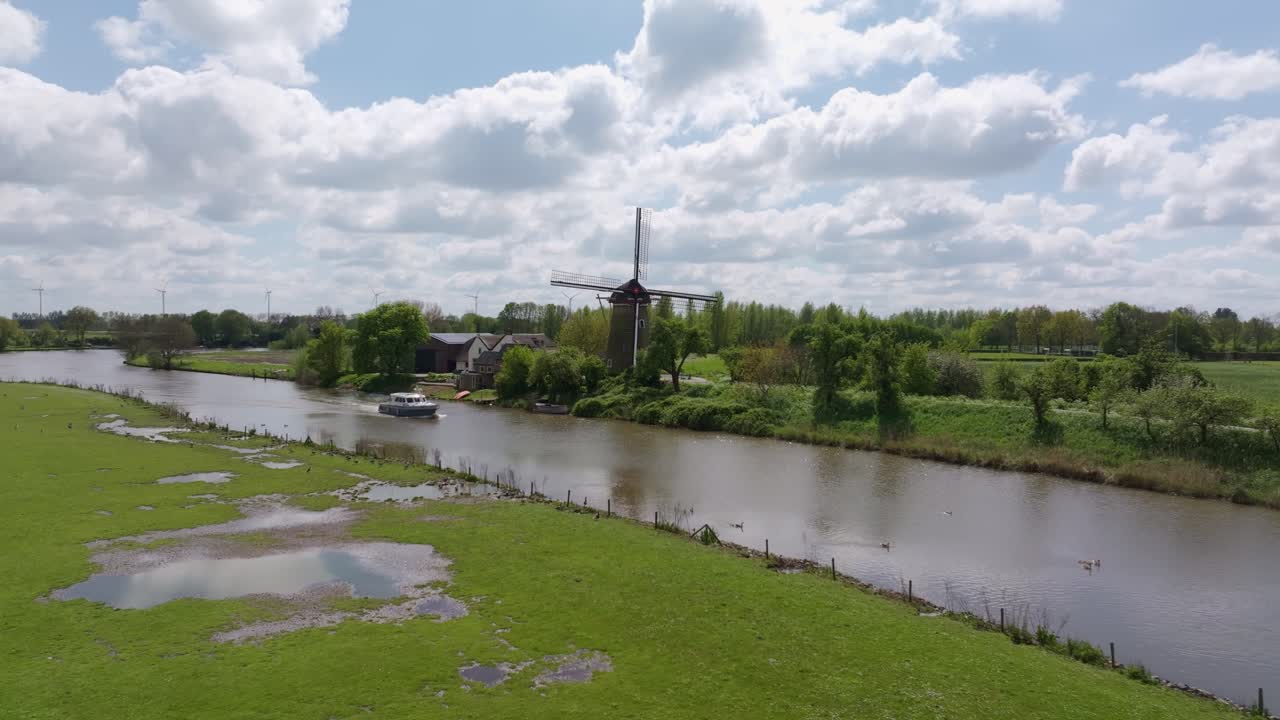 Bateau glissant sur la rivière Linge près d'un moulin à vent au milieu des champs, Pays-Bas