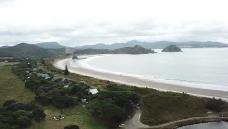 Aerial-shot,-tracking-a-sea-legs-from-ocean-onto-the-road,-[tracking-the-boat-on-the-road-from-behind]-Great-Barrier-Island,-New-Zealand