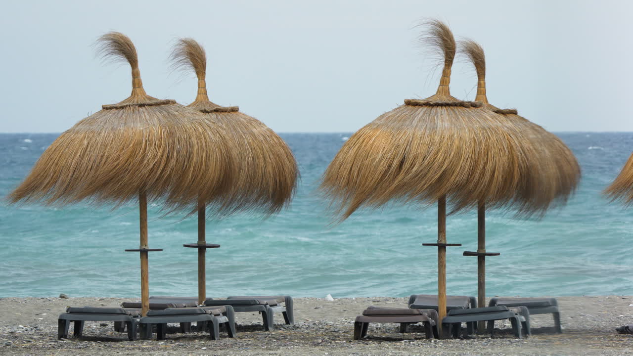 playa vacía con sombrillas de paja y vista al océano