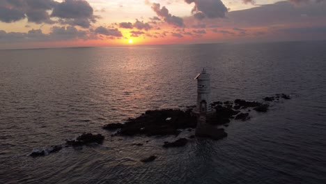 breathtaking aerial view of lighthouse on offshore rocks in calasetta, sunset