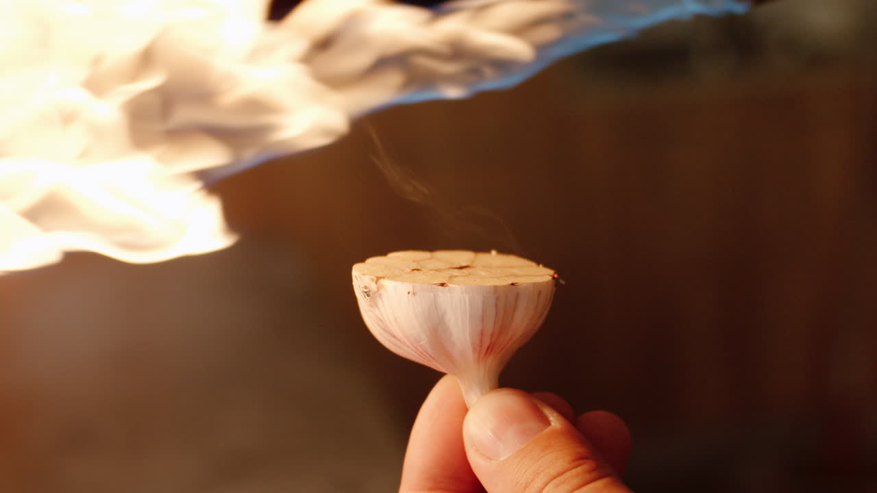 Garlic bulb sliced in half getting scorched by flames from kitchen burner