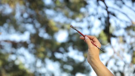 happy girl artist paints a picture on the background of summer nature hobbies creativity - happy girl artist paints a picture on the background of summer nature. a woman with a brush and a palette makes a sketch. hobbies, creativity, leisure time