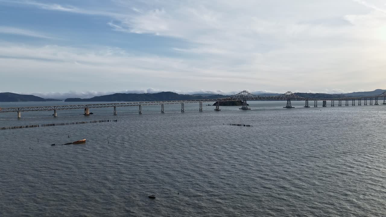 An aerial time-lapse captures the Richmond-San Rafael Bridge as traffic glides across the span under a vivid sky.