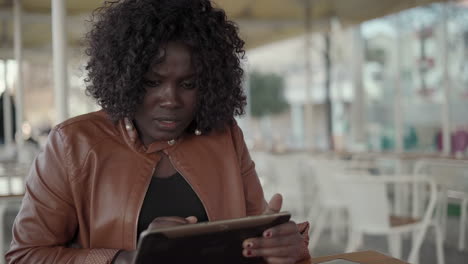 serious young woman using cell phone and tablet pc in cafe