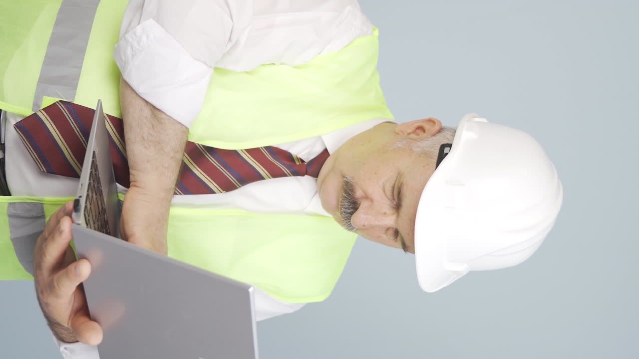 노인 엔지니어가 노트북에서 프로젝트를 진행하는 수직 비디오입니다.