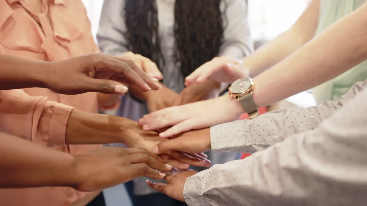sección media de diversas mujeres de negocios apilando las manos en la oficina, en cámara lenta