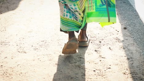 siguiendo a una mujer india caminando por una calle de tierra