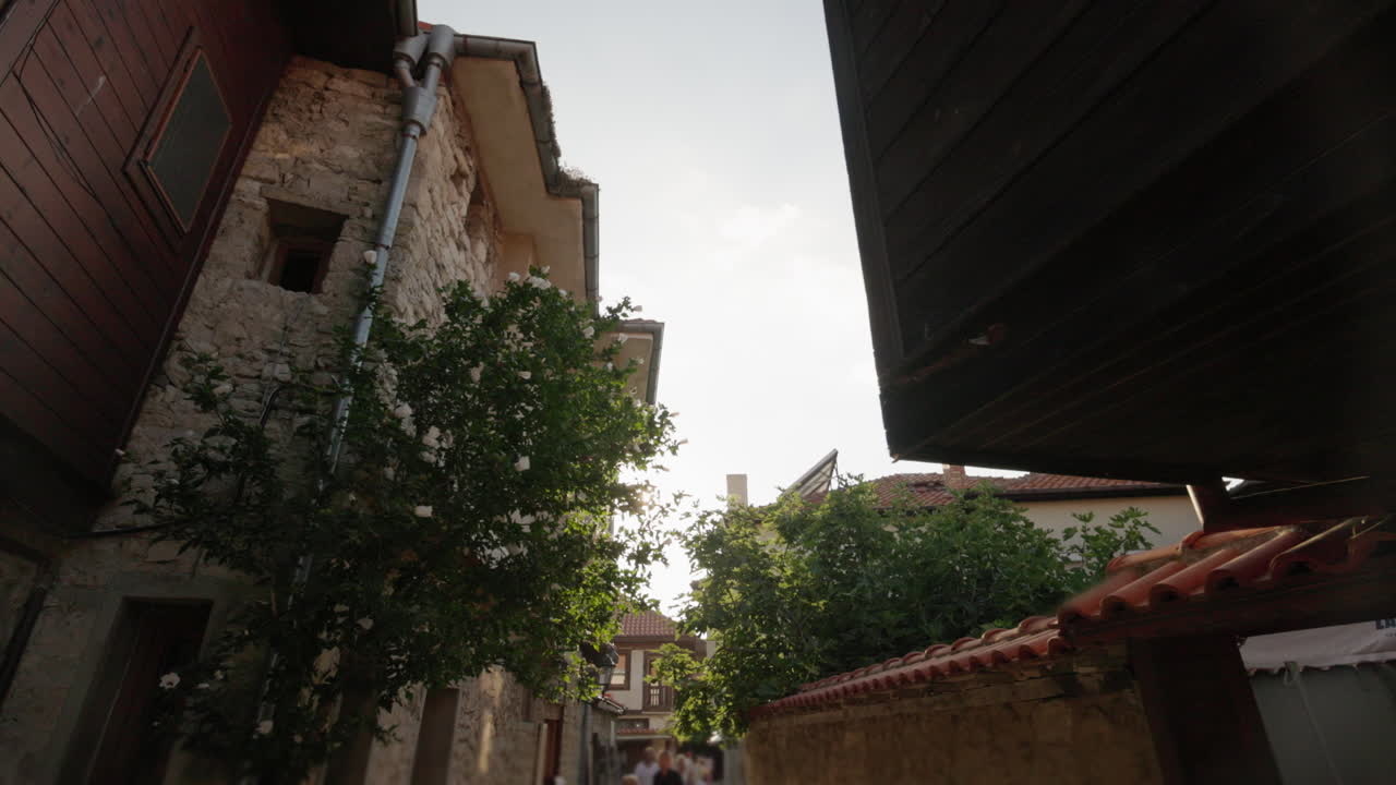 Rua estreita e antiga de Nesebar com casas de madeira, luz solar e clarão da lente em perspectiva em movimento