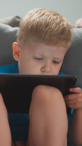child sits next to mother on couch, watches cartoons, plays tablet, close-up, slow motion