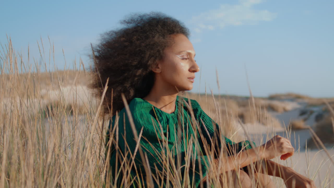 Relaxed woman sitting desert with dry grass close up. Girl looking in distance.