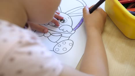 little girl colouring adorable bunny in children book learning precision, slow motion