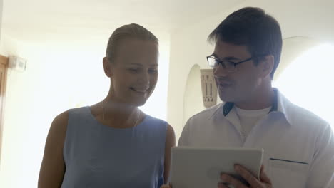 Doctor-with-tablet-talking-to-female-patient