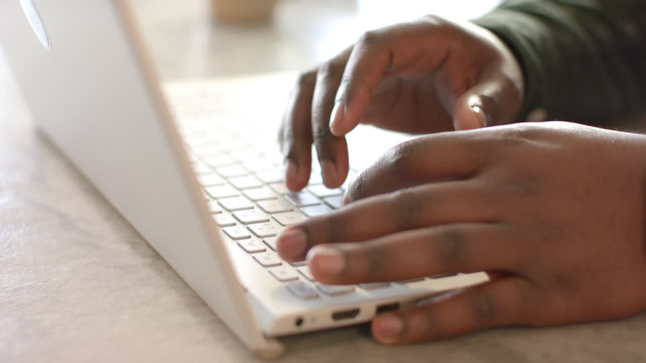 Hands entering frame are settling on laptop keys and typing rapidly for work, pausing then resuming