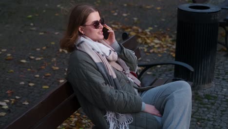 woman talking on phone in park during autumn