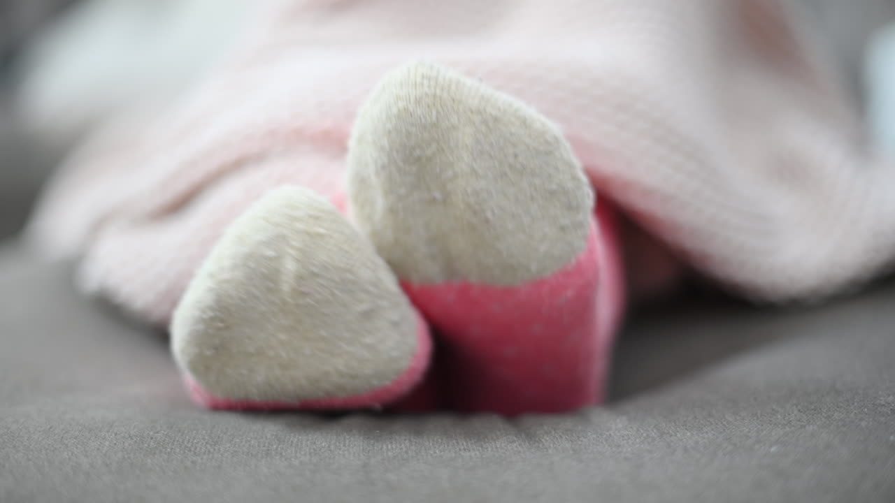 Woman moving feet in winter wool socks, close up, pink blanket
