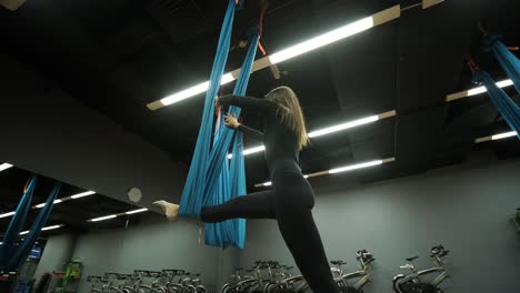 attractive woman doing aero yoga stretching exercises in hammocks at fitness studio. healthy lifestyle for female. workout gym