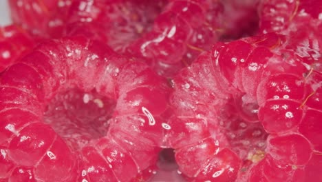 Extreme-macro-shot-juicy-textured-Raspberries-water-falling-over,-Slow-motion