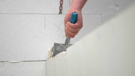 worker's hand applying waterproofing coat on concrete wall