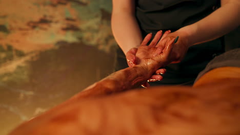 chocolate massage - therapist massaging hand of woman with chocolate to nourish and smooth the skin