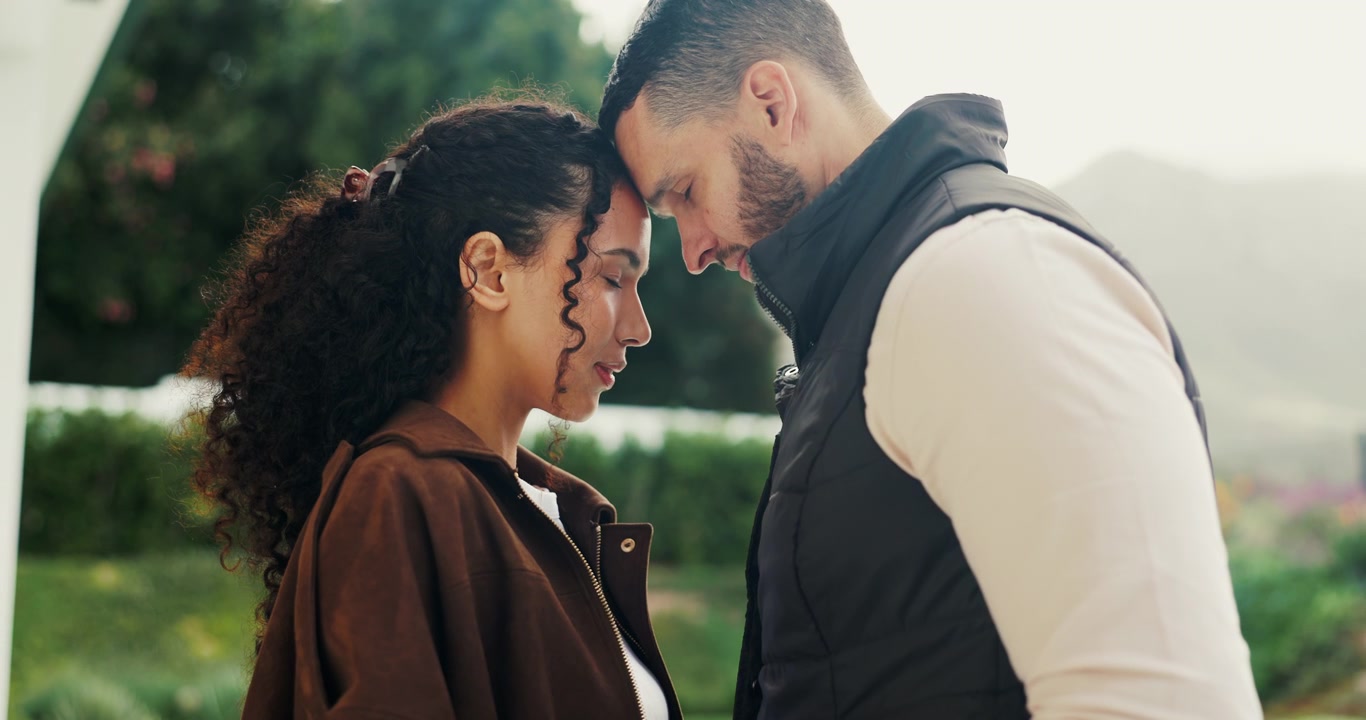 Couple Standing Together With Foreheads Touching Outdoors