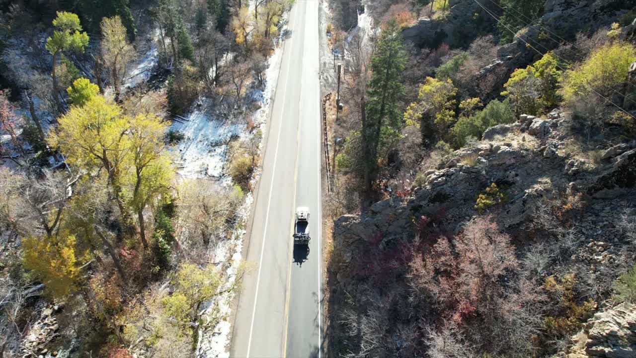 Driving down a lush mountain road after a day of skiing. There are remnants of snow on the side of the road but the trees are still green and the sun is still out!
