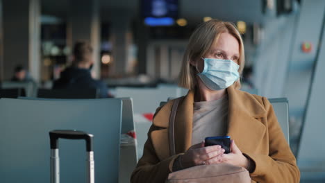 retrato de una mujer con una máscara protectora, sentada en la terminal del aeropuerto esperando el vuelo