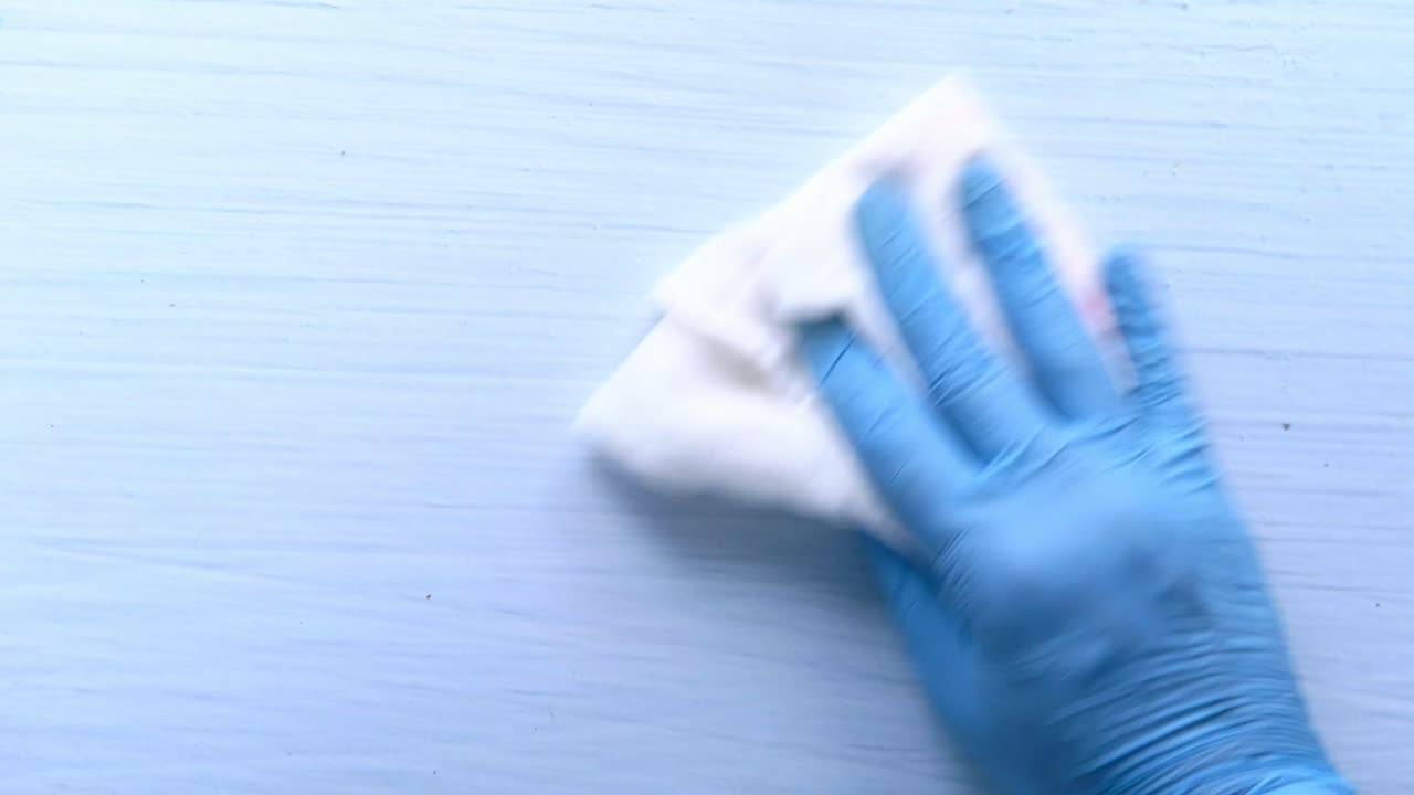 limpieza de una superficie azul claro con guantes