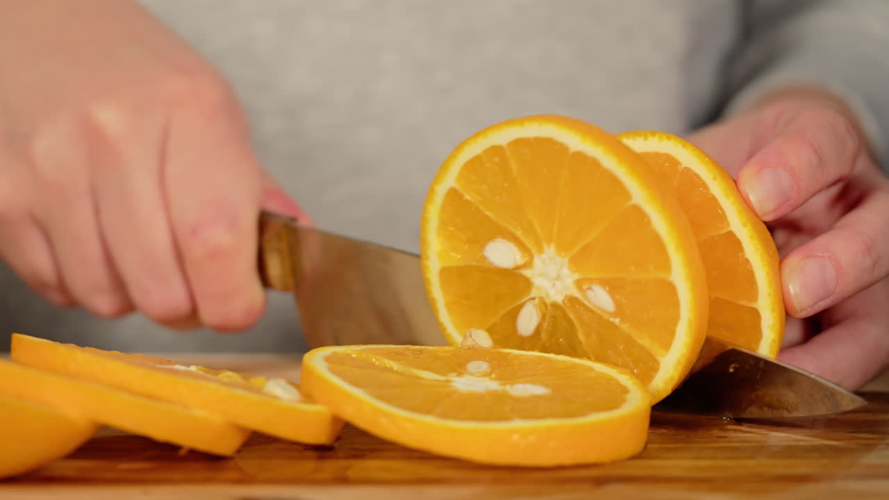 Close-Up de Mãos Fatiando uma Laranja Fresca em uma Tábua de Madeira