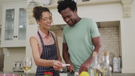 Glückliches-Gemischtrassiges-Paar,-Das-Zusammen-Kocht-Und-Gemüse-Schneidet