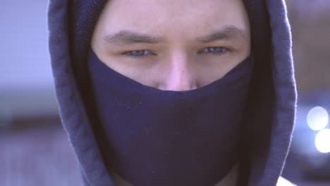 young handsome man with his hoodie wearing a black protective facemask during the coronavirus outbreak