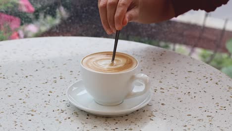 agitando el café a mano en una taza blanca