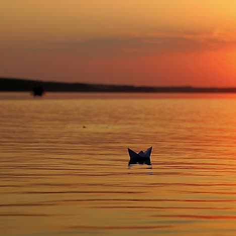 paper boat sailing at sunset