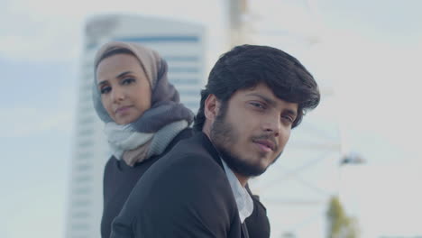 serious arab man and woman standing in city and looking at camera