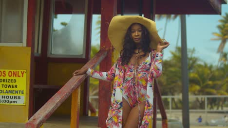 Amazing-orbital-pan-of-a-young-lady-standing-at-the-base-of-a-lifeguard-booth-in-a-bikini