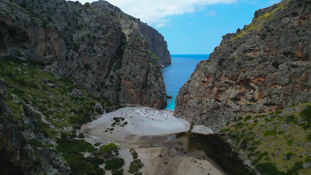 Aerial pullback reveals Sa Calobra beach nestled between steep cliffs and turquoise water Mallorca, Spain