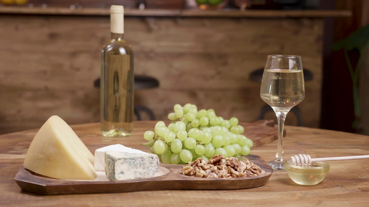 Cheese, wine, grapes, nuts, and honey on a wooden table