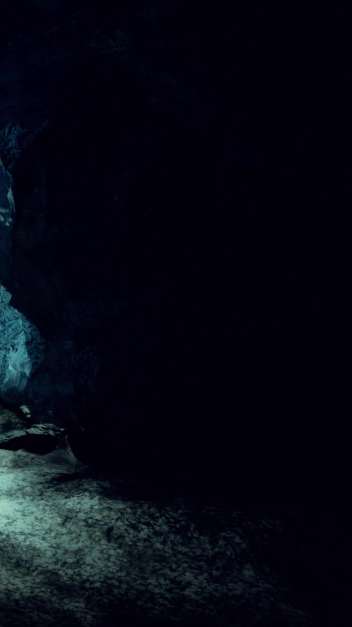 Exploring a dark cave with light breaking through cracks in the rock