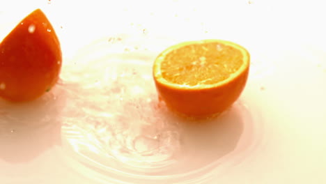 mitades naranjas que caen y rebotan en una superficie blanca y húmeda